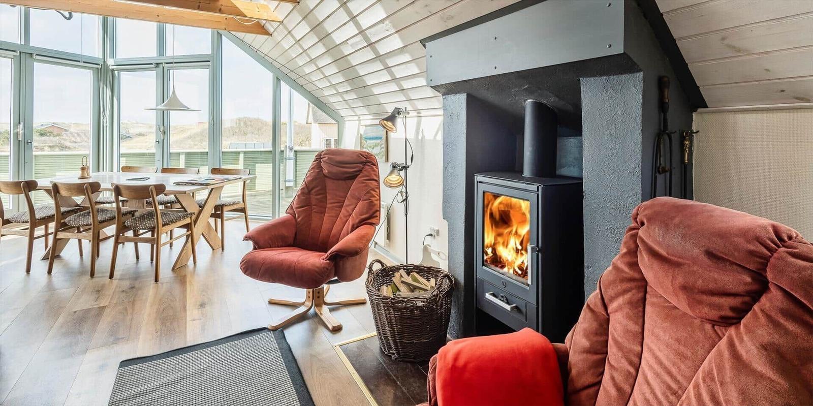 Wohn- und Essbereich mit Kamin, Sessel und großem Fenster