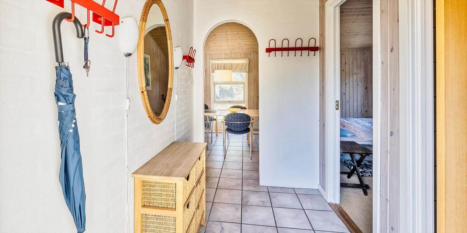 Eingangsbereich mit Garderobe, Spiegel und Holzschrank. Durchgang zu Esszimmer und Schlafzimmer.