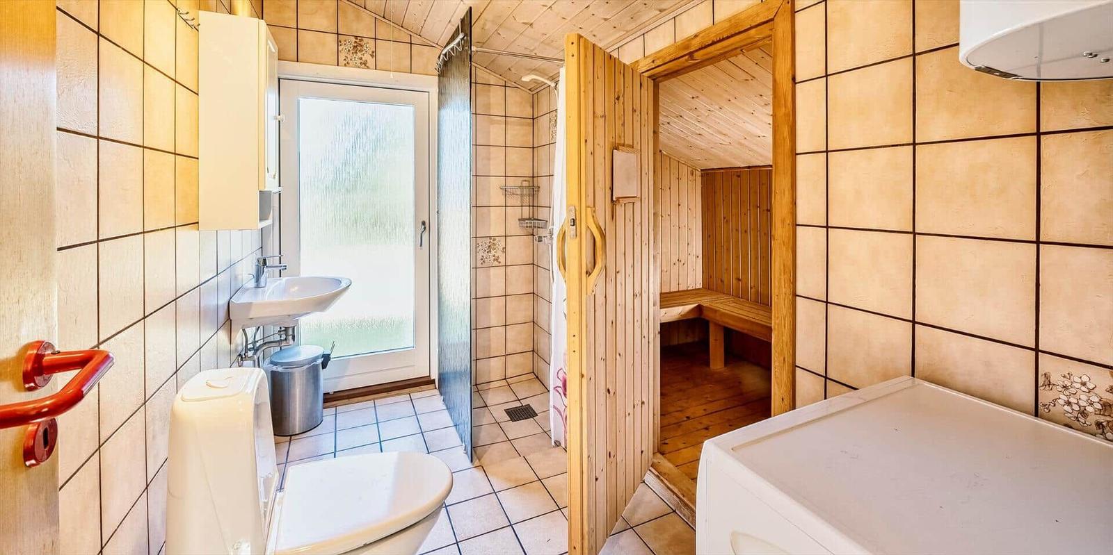 Badezimmer mit Dusche, Toilette, Waschbecken und Sauna.