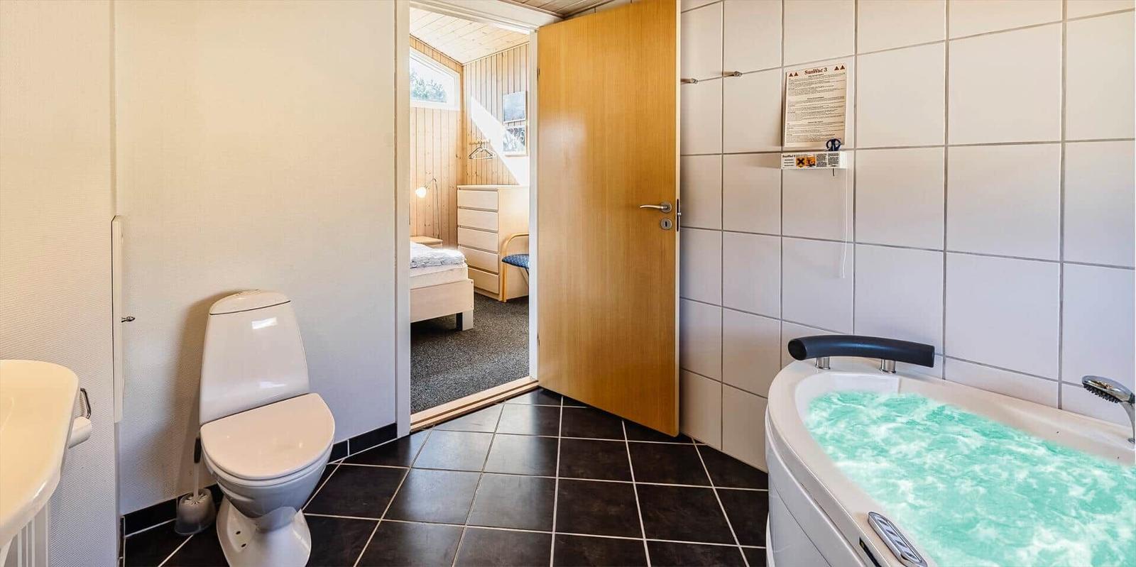 Bad mit Whirlpool, Toilette und Blick in Schlafzimmer