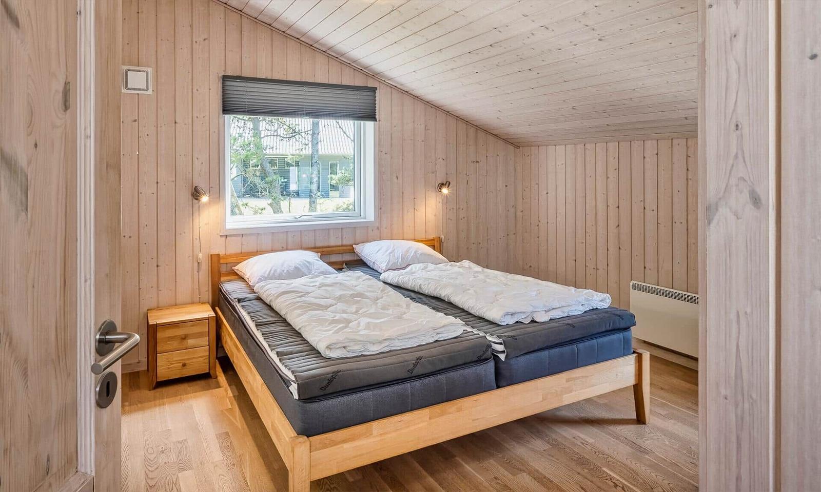 Schlafzimmer mit Holzwand, Bett und Fenster