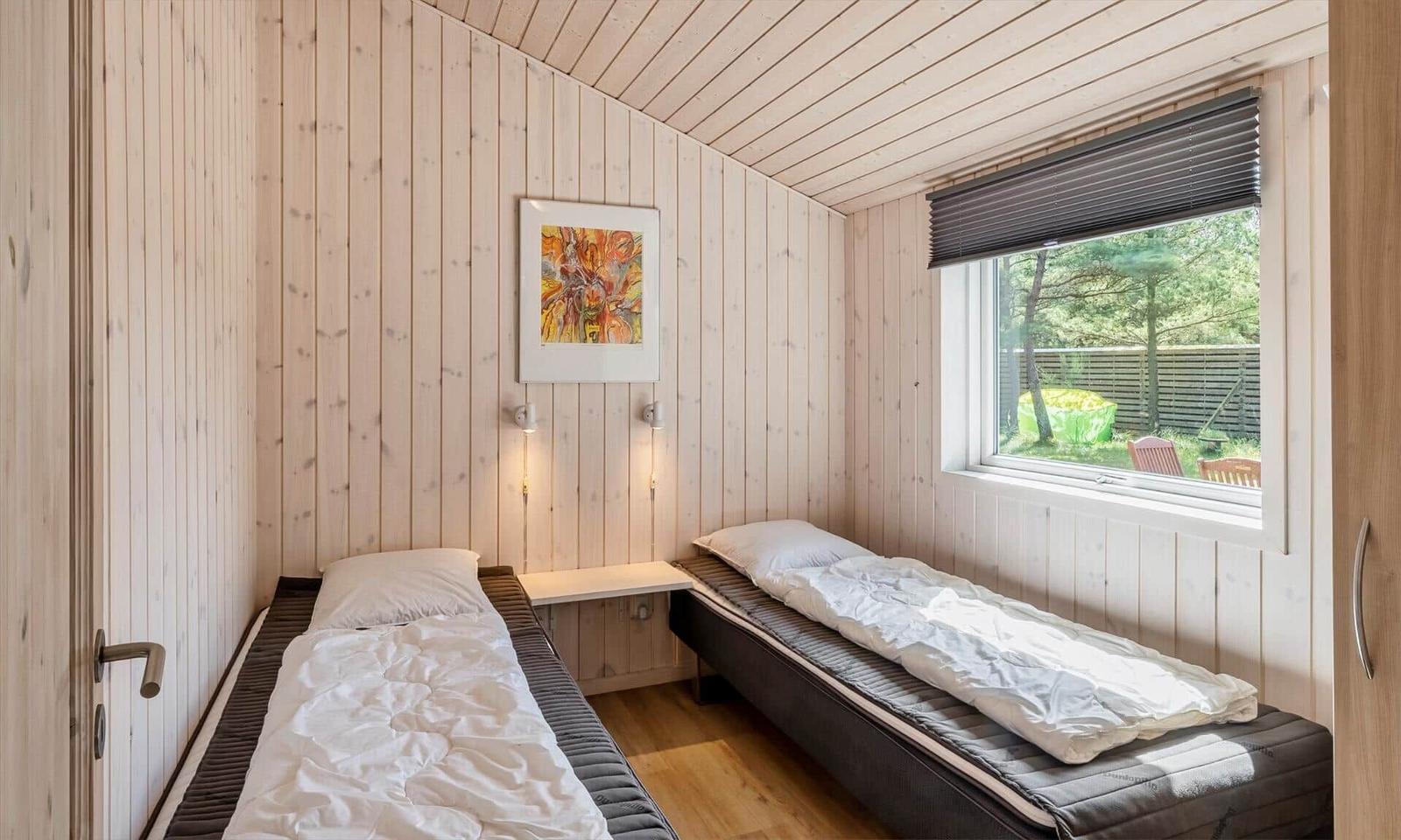Zwei Betten in einem Holzraum mit Fenster und Wandbild.