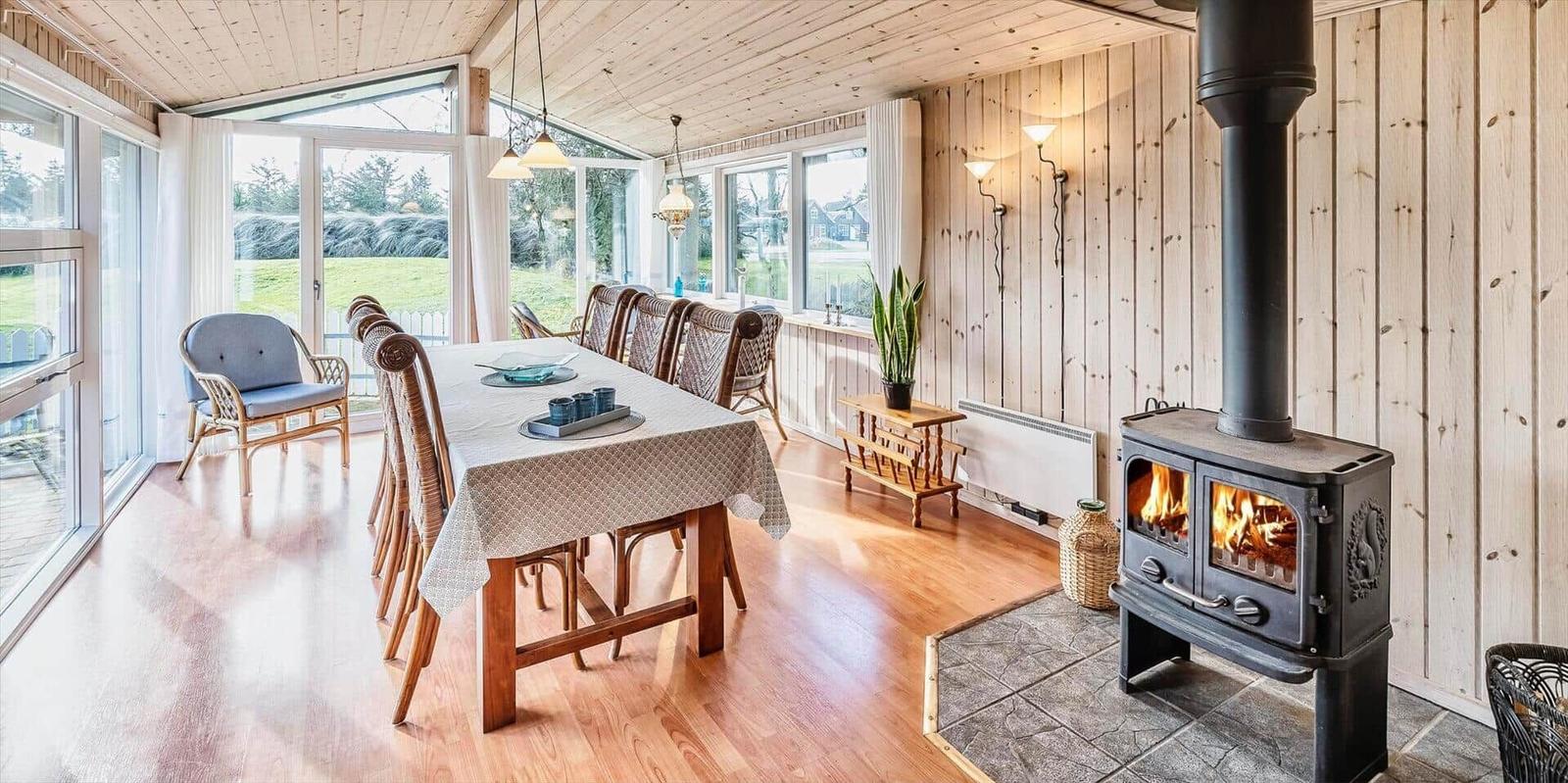 Esszimmer mit Holzwand, Kamin und großem Fensterblick auf Garten