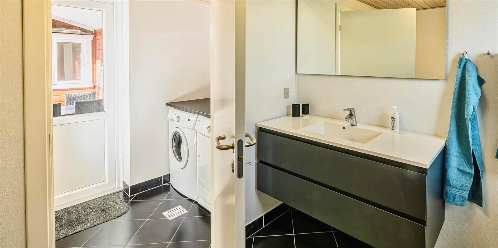 Badezimmer mit Waschmaschine und Spiegelschrank. Türklinken und Handtuch an der Wand.