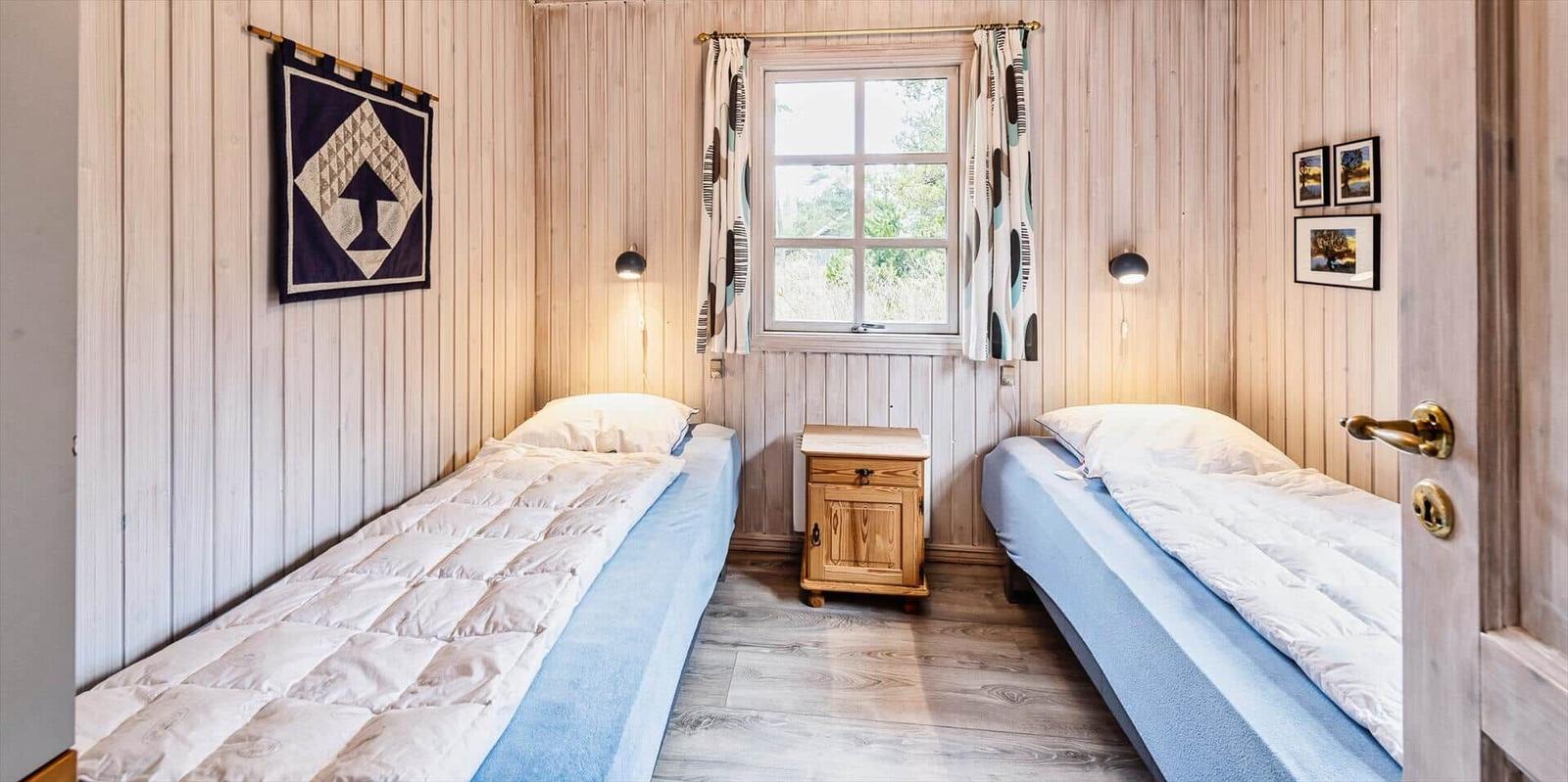 Zwei Einzelbetten, ein Fenster, Holzwand und Nachttisch