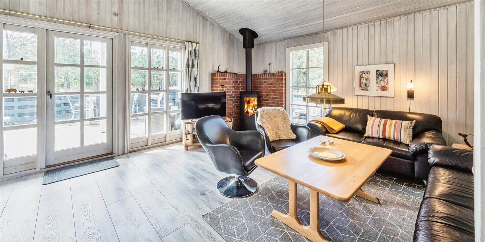 Wohnzimmer mit Holzfußboden, Sofa, Stühlen und Kaminofen.