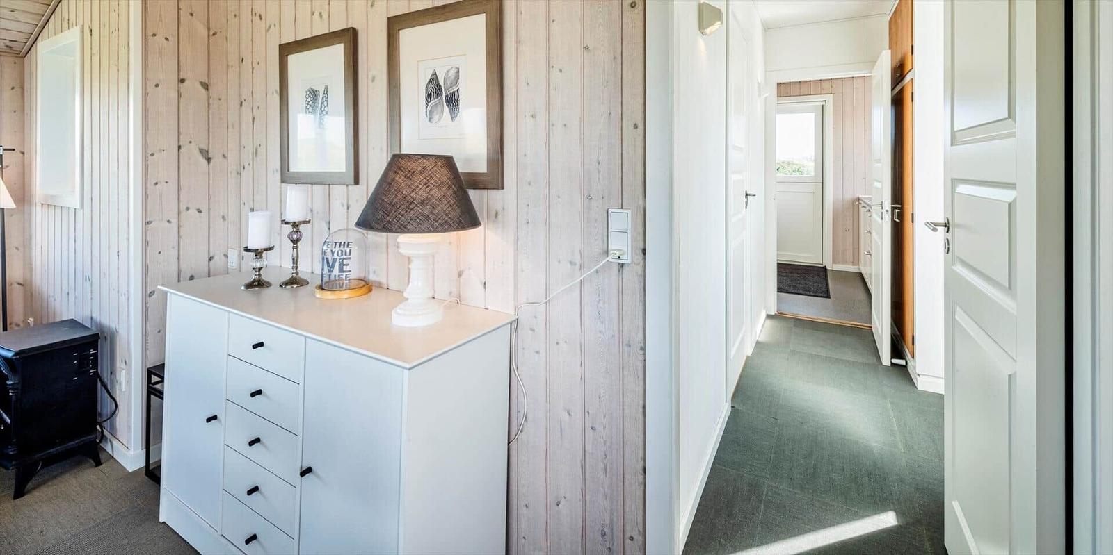 Flur mit weißen Türen und Holzwand. Schrank mit Lampe und Bildern.