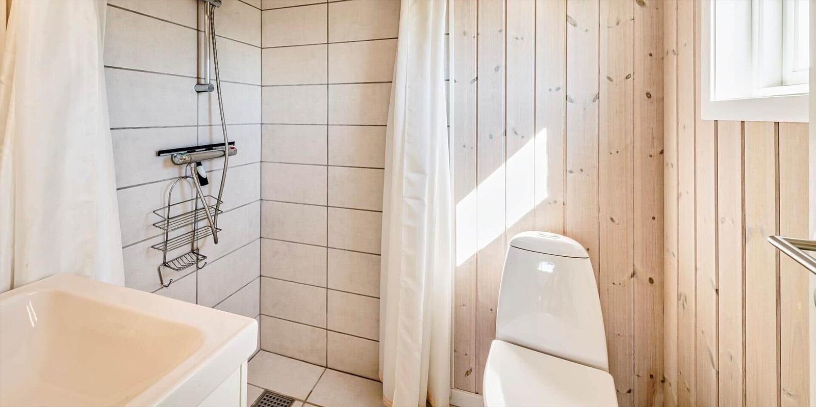 Badezimmer mit Dusche, Toilette und Waschbecken.