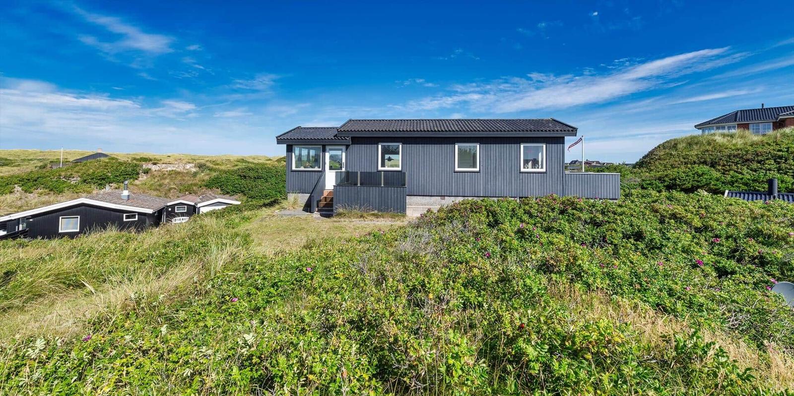 Moderne Strandhaus mit Blick auf Dünen und klarem Himmel.
