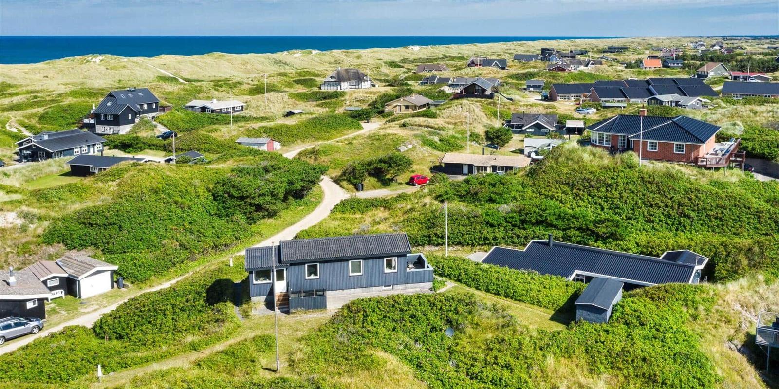 Häuser auf grünen Dünen mit Blick auf das Meer.