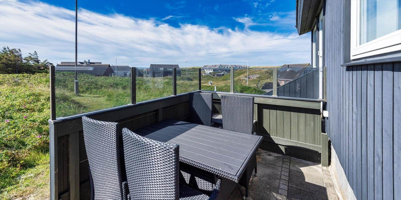 Terrasse mit Sitzgruppe und Blick auf grüne Hügel und Häuser.