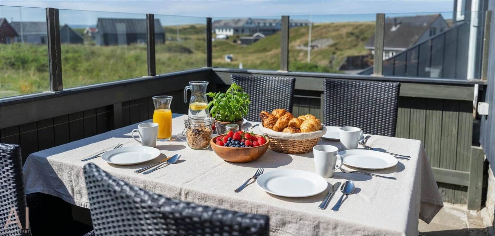 Frühstückstablett auf Terrasse mit Blick auf Hügel und Häuser.