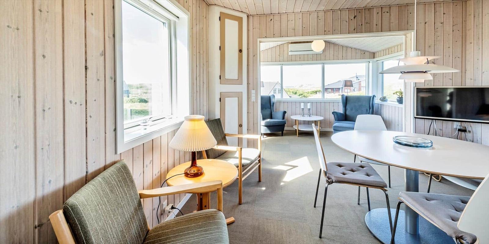 Wohnzimmer mit Essbereich, Holzwand und Fensterblick
