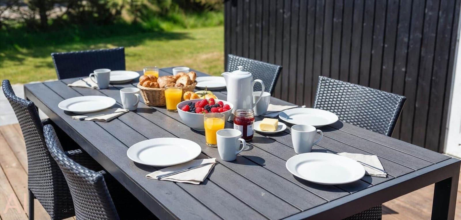 Gedeckter Essbereich im Freien mit Tisch, Stühlen und Frühstück.