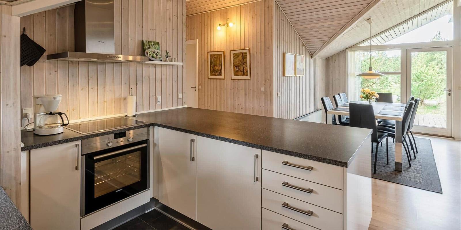 Küche mit Essbereich, Holzwand und Glasfront zum Garten.