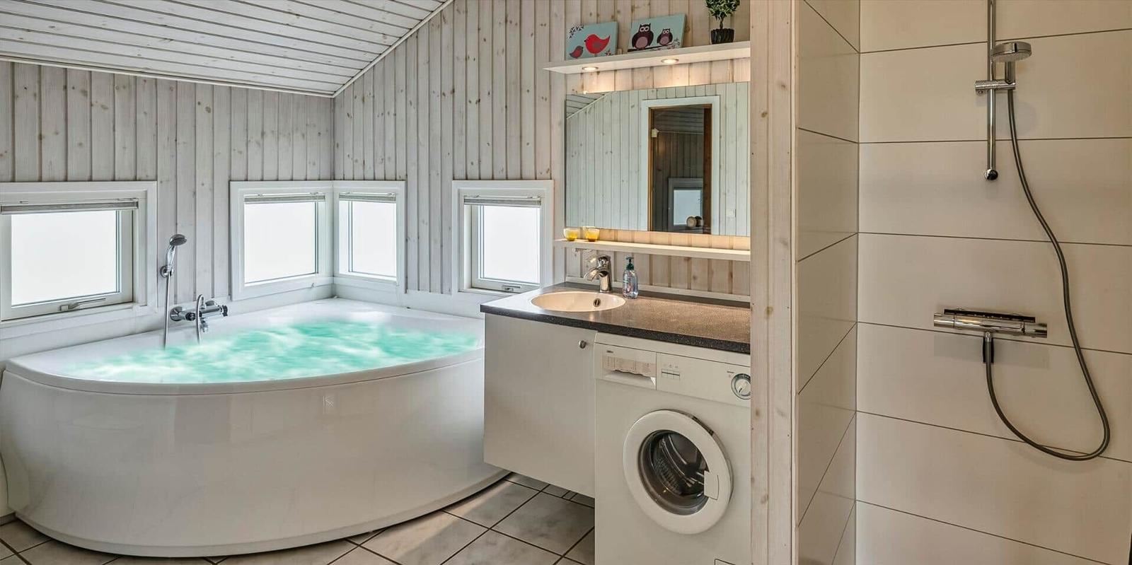 Bad mit Whirlpool, Dusche und Waschmaschine. Holzwände und Fenster.