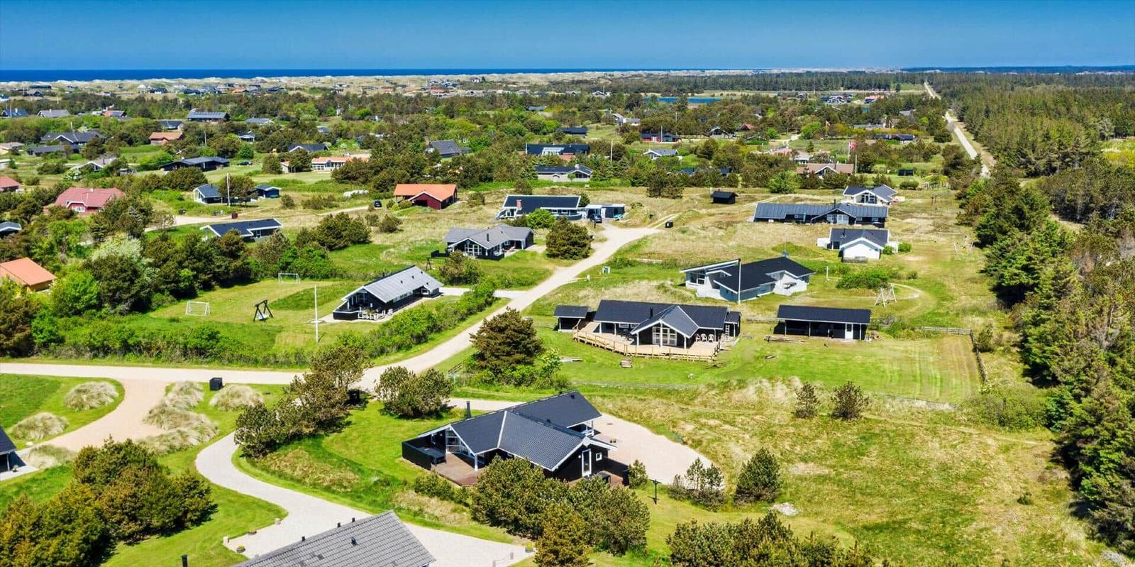 Luftbild von Ferienhäusern in einer grünen Landschaft mit Blick aufs Meer.
