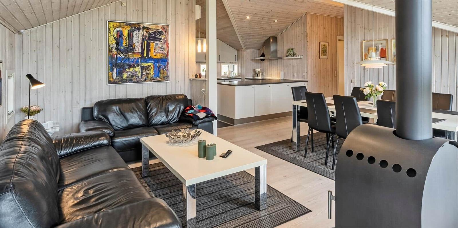 Wohnzimmer mit Ledersofa, Esstisch und Küchenbereich