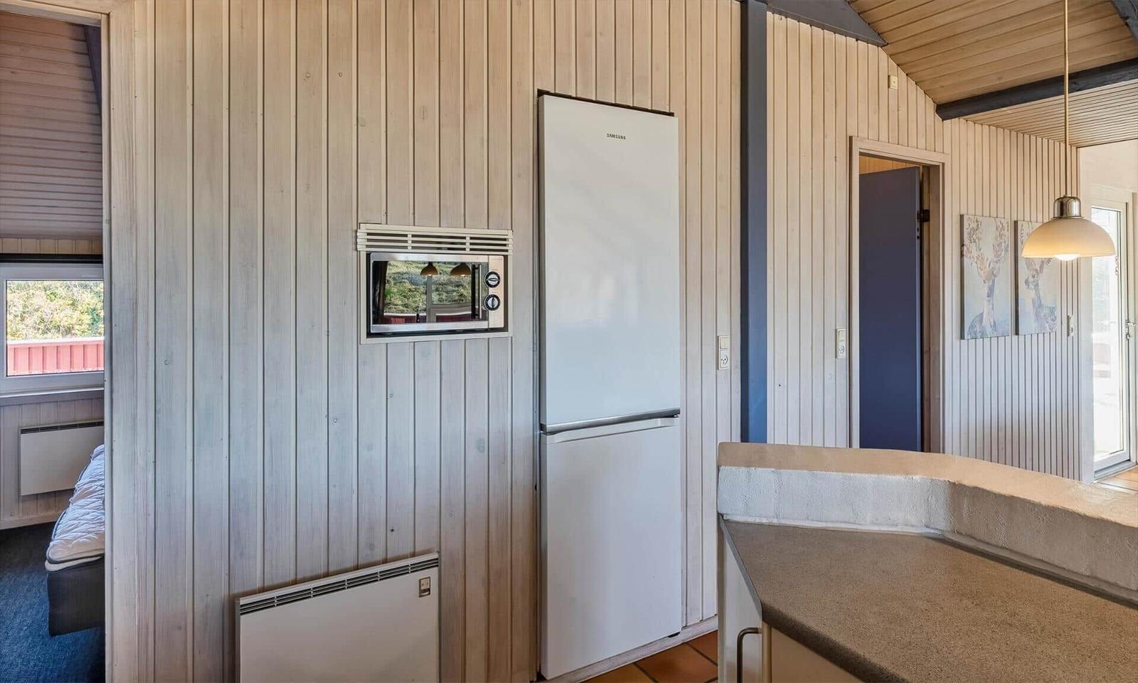 Küche mit Kühlschrank und eingebauter Mikrowelle an Holzwand
