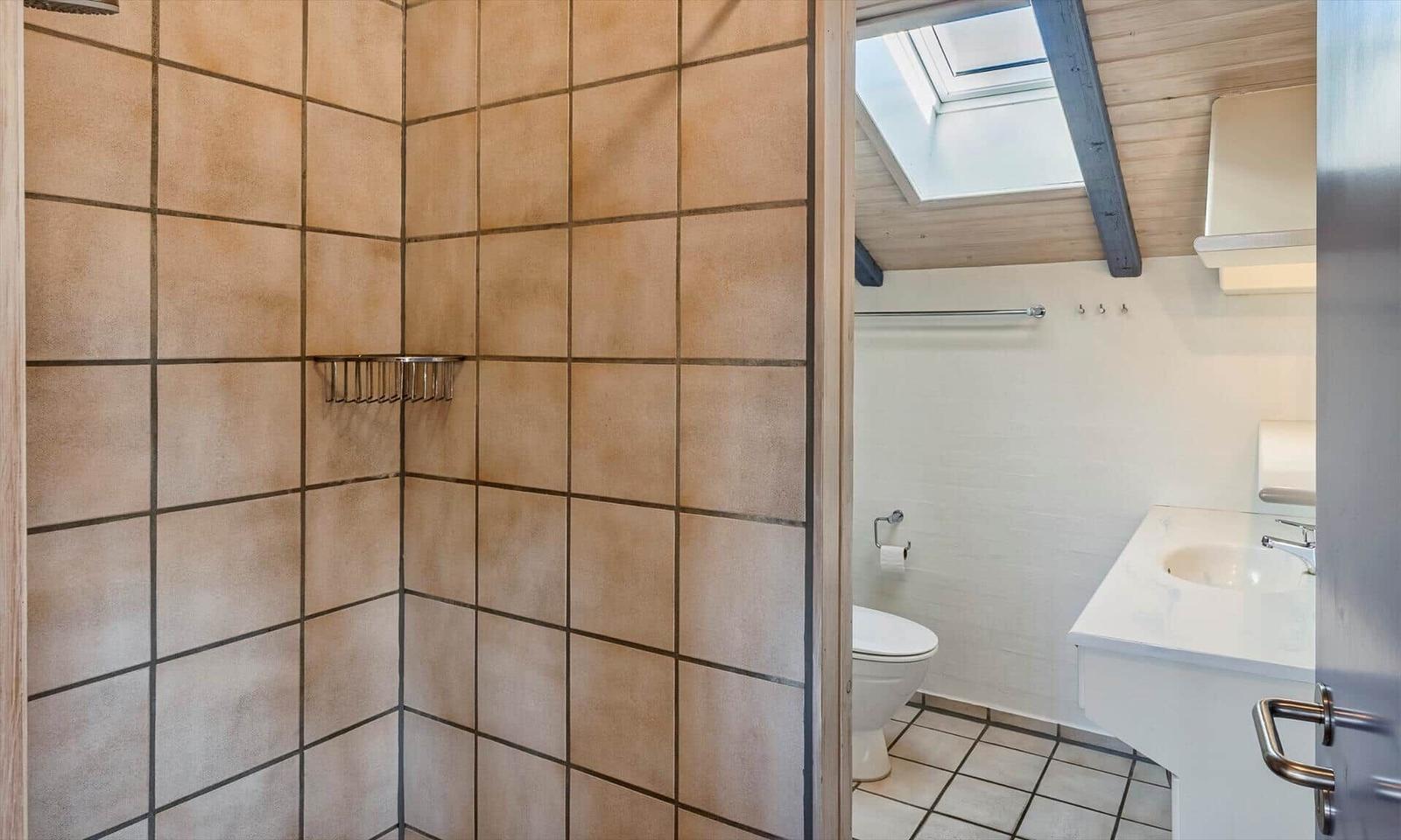 Badezimmer mit Dusche, Toilette und Waschbecken unter Dach