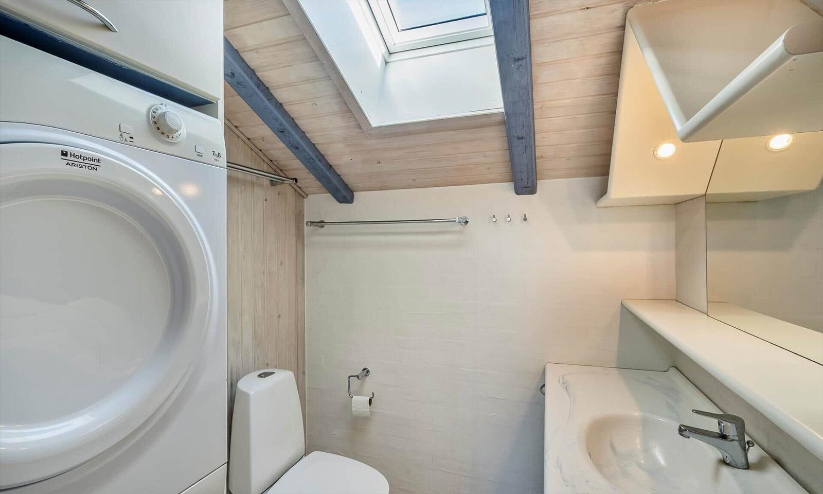 Badezimmer mit Waschmaschine, Toilette und Waschbecken unter Dachschrägen.