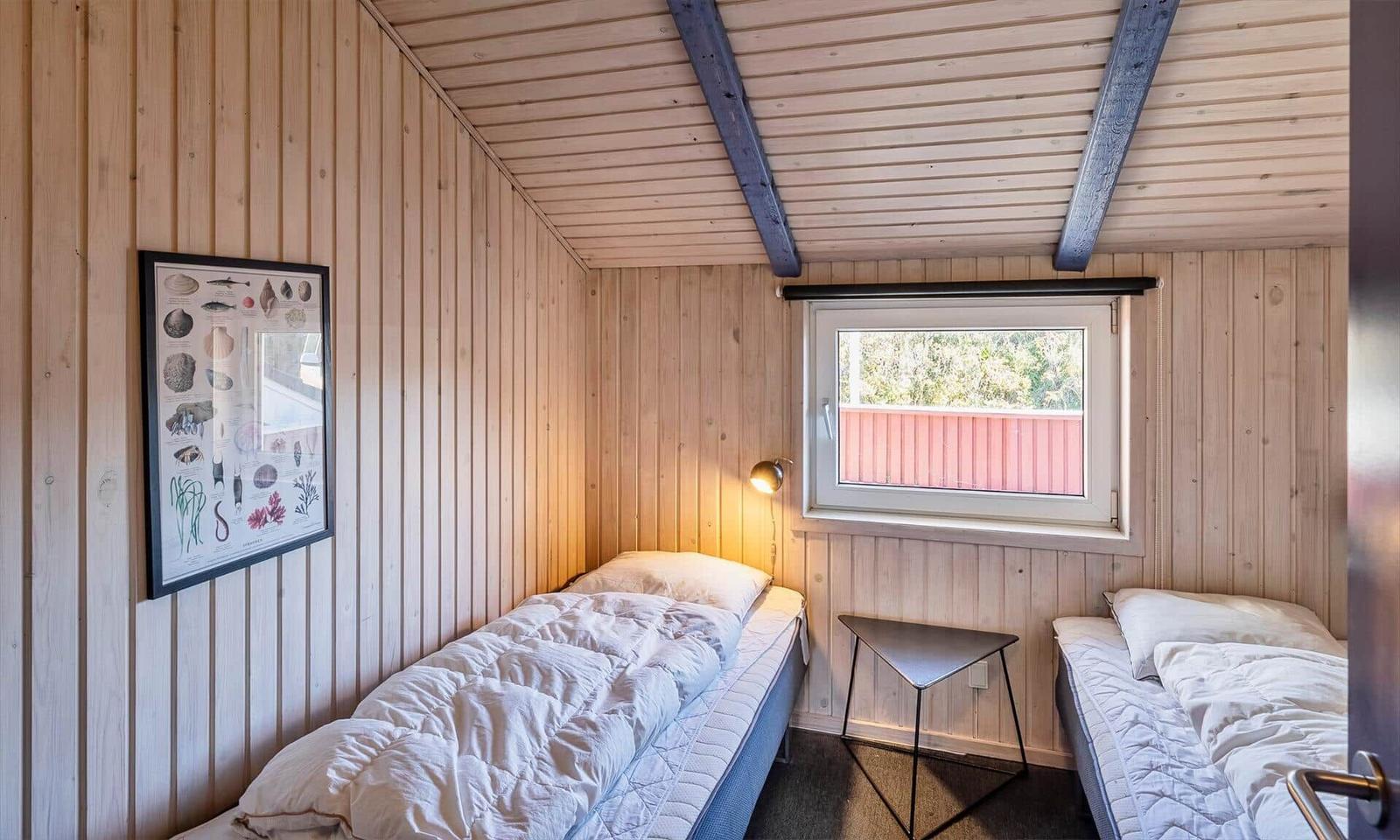 Zwei Betten, Holzwände, Fenster und Bild an der Wand.