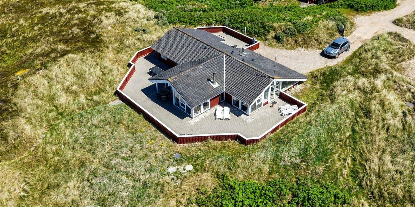 Haus mit Terrasse und Grillplatz auf grüner Wiese.