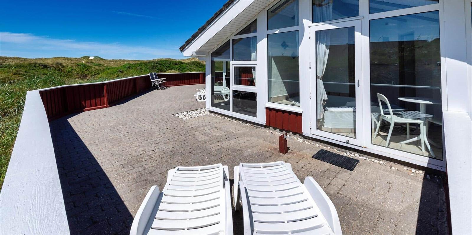 Terrasse mit Liegestühlen und Blick auf Dünen