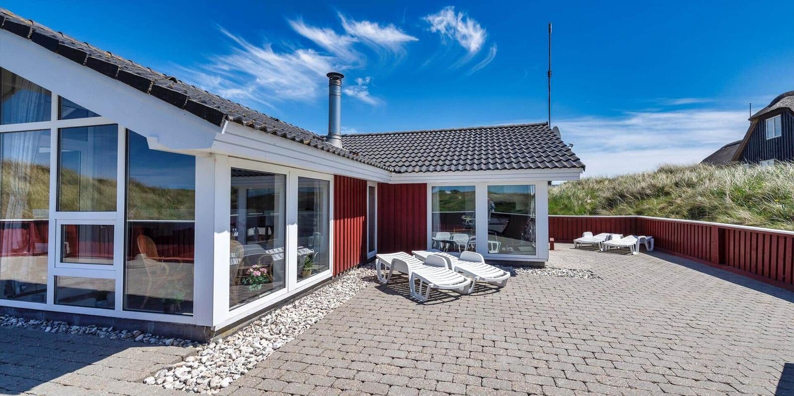 Wohnhaus mit Terrasse, Liegen und Blick auf Dünen.