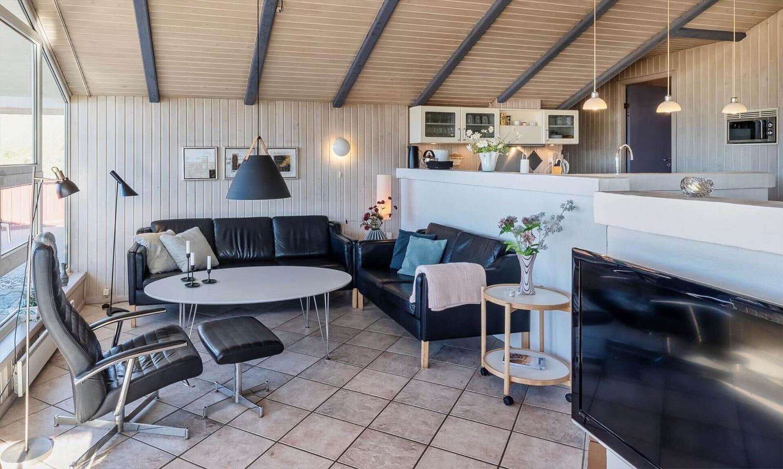Wohnbereich mit Sofa, Sessel und Küchenzeile.