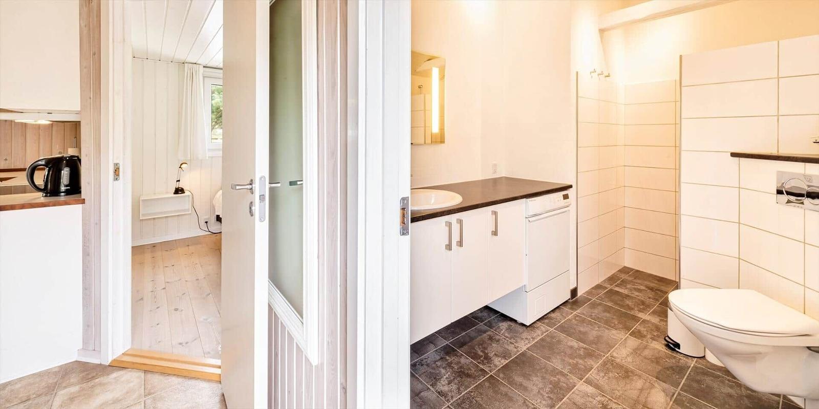 Badezimmer mit Waschmaschine, Toilette und Dusche. Küche und Schlafzimmer sind sichtbar.