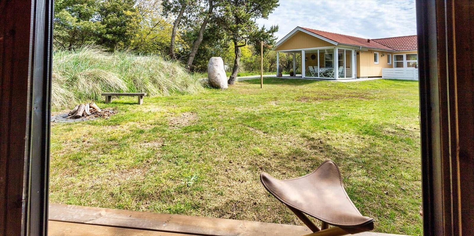Vorgarten mit Gras, Stein und Bank. Im Hintergrund Haus mit Terrasse.