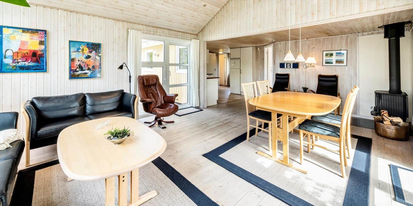 Wohn- und Essbereich mit Holzmöbeln, Sofa und Kaminofen.