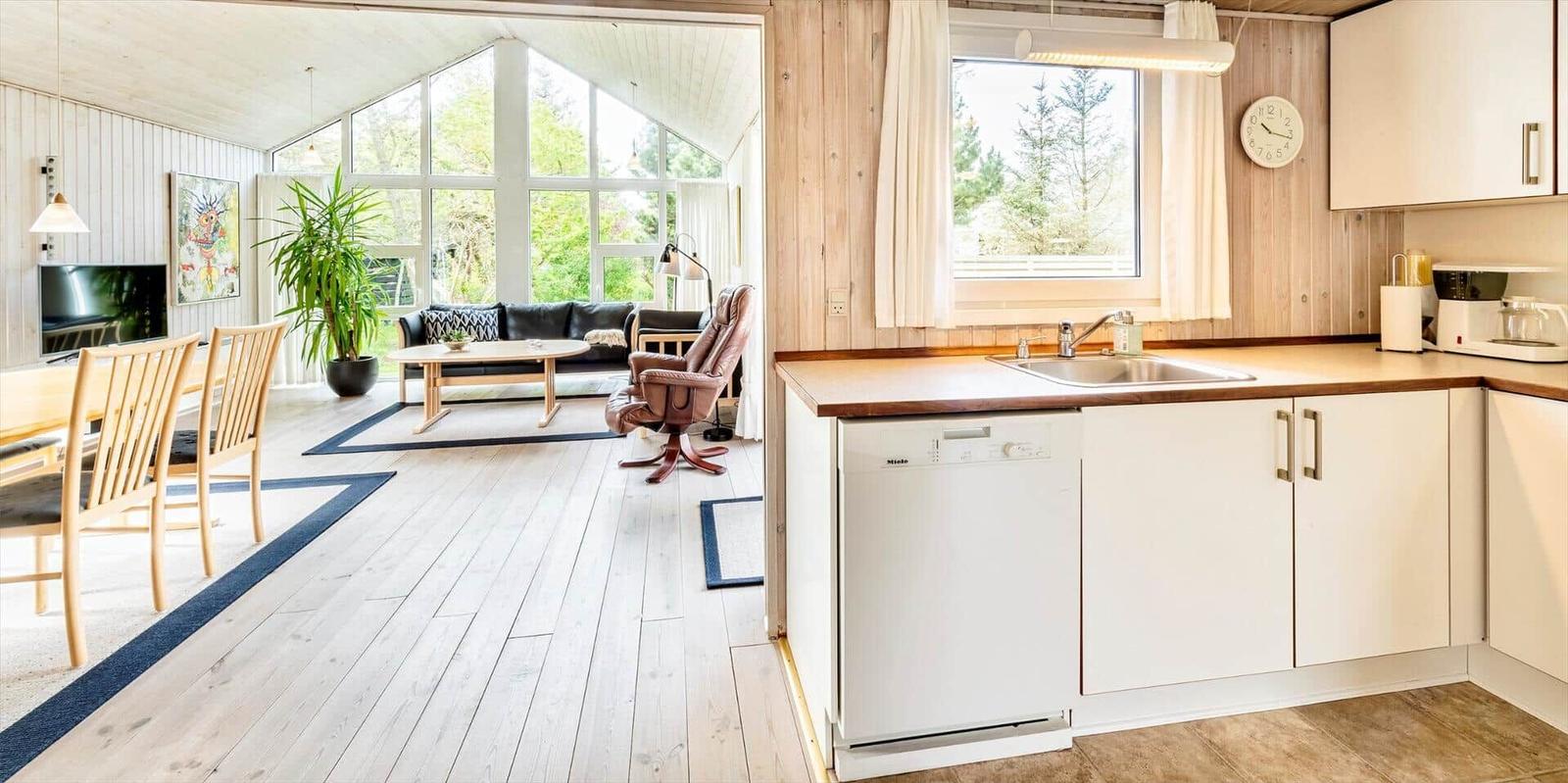 Küche mit Waschmaschine und Blick in Wohnzimmer mit Sofa und Tisch.