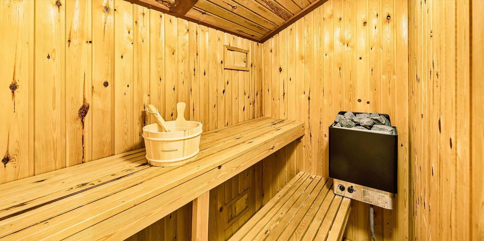 Sauna mit Holzbank, Eimer und Heizung.
