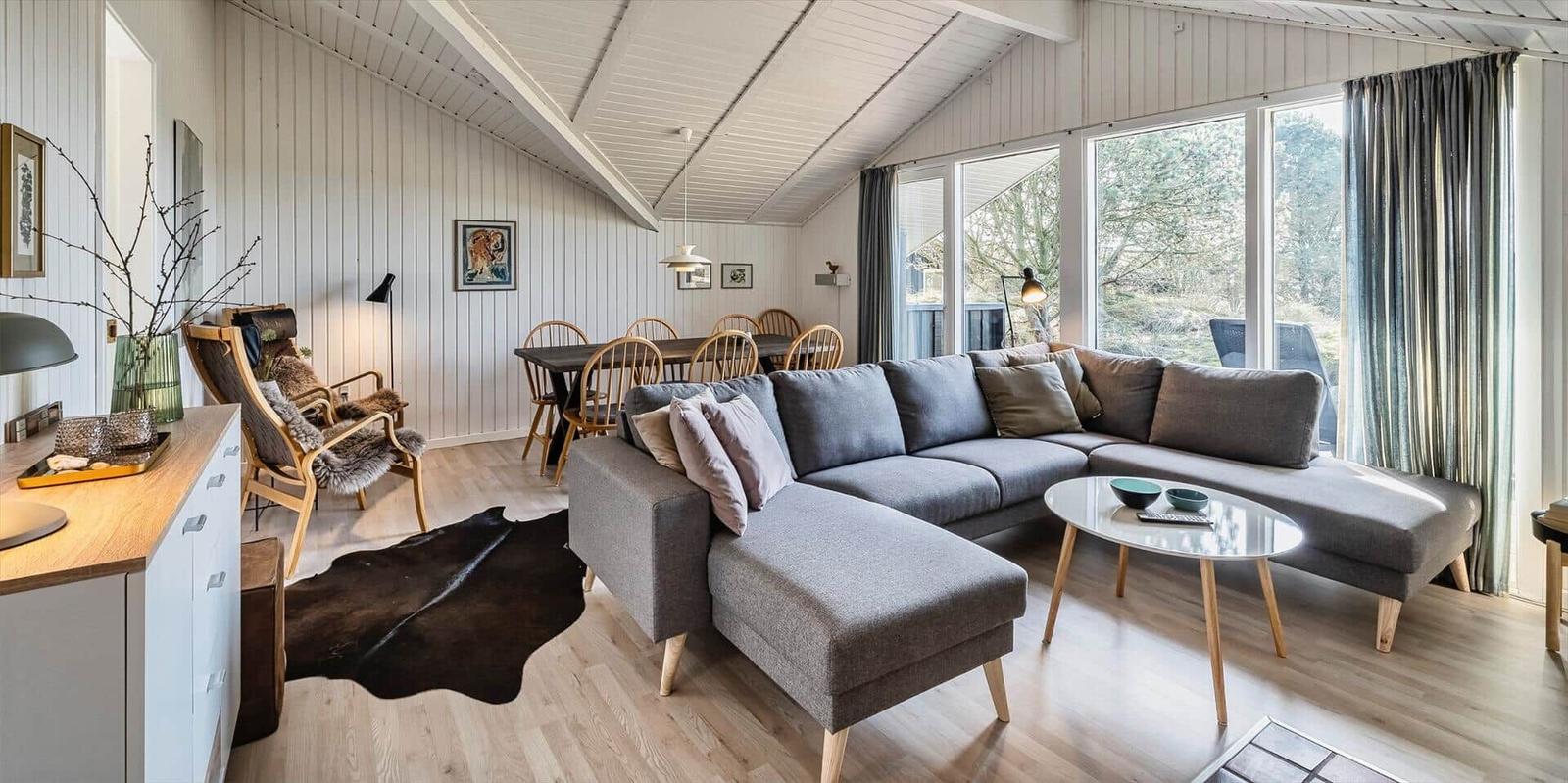 Wohnzimmer mit großem Sofa, Esstisch und Blick auf den Garten