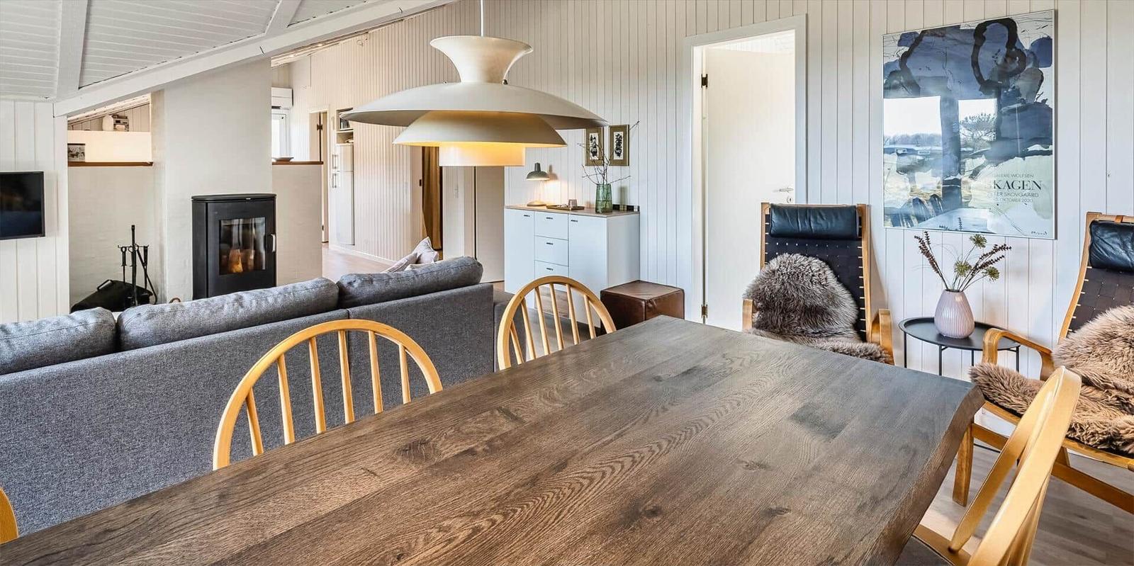 Essbereich mit Holztisch und Stühlen, Sofa, Kamin und Wandbild.