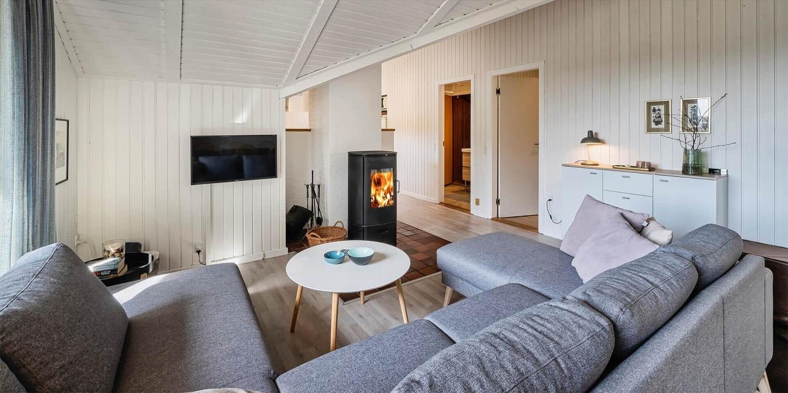 Wohnzimmer mit grauem Sofa, Kamin und Fernseher an der Wand.