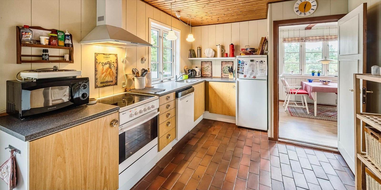 Küche mit Holzschrank, Steinplatten und Blick in Esszimmer