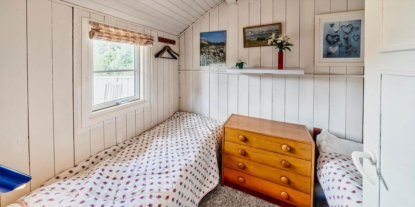 Schlafzimmer mit zwei Betten, Schrank und Fenster mit Blick.