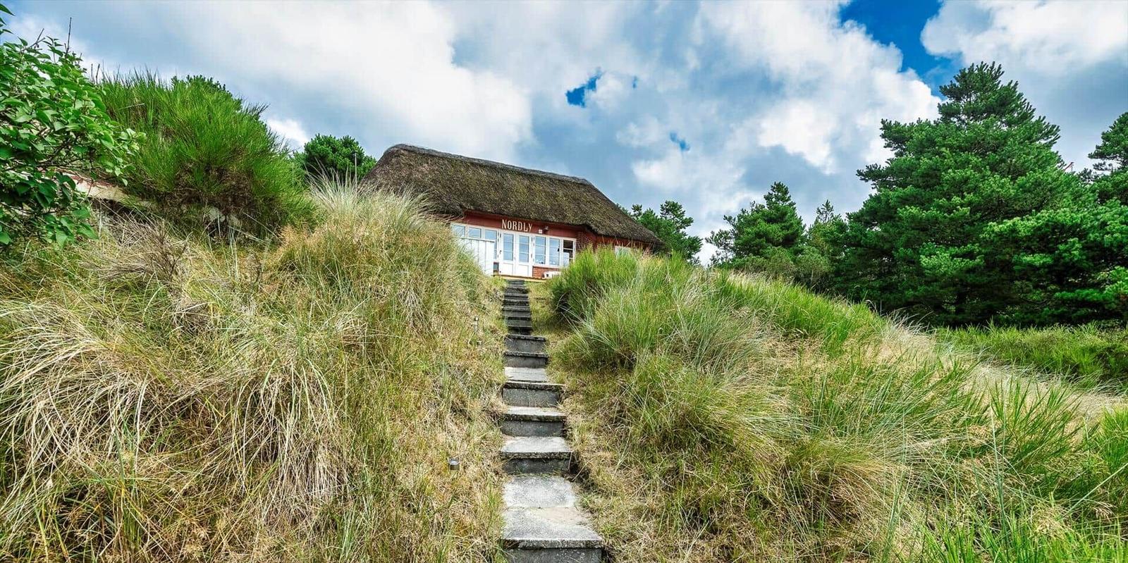 Haus mit Stiegenweg und Grasbewuchs unter blauem Himmel