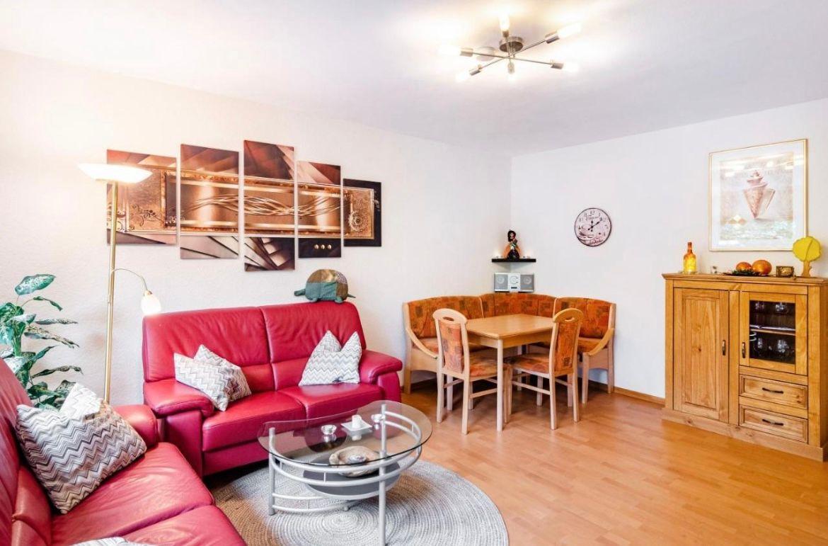 Wohn- und Essbereich mit rotem Sofa, Esstisch und Holzmöbeln.