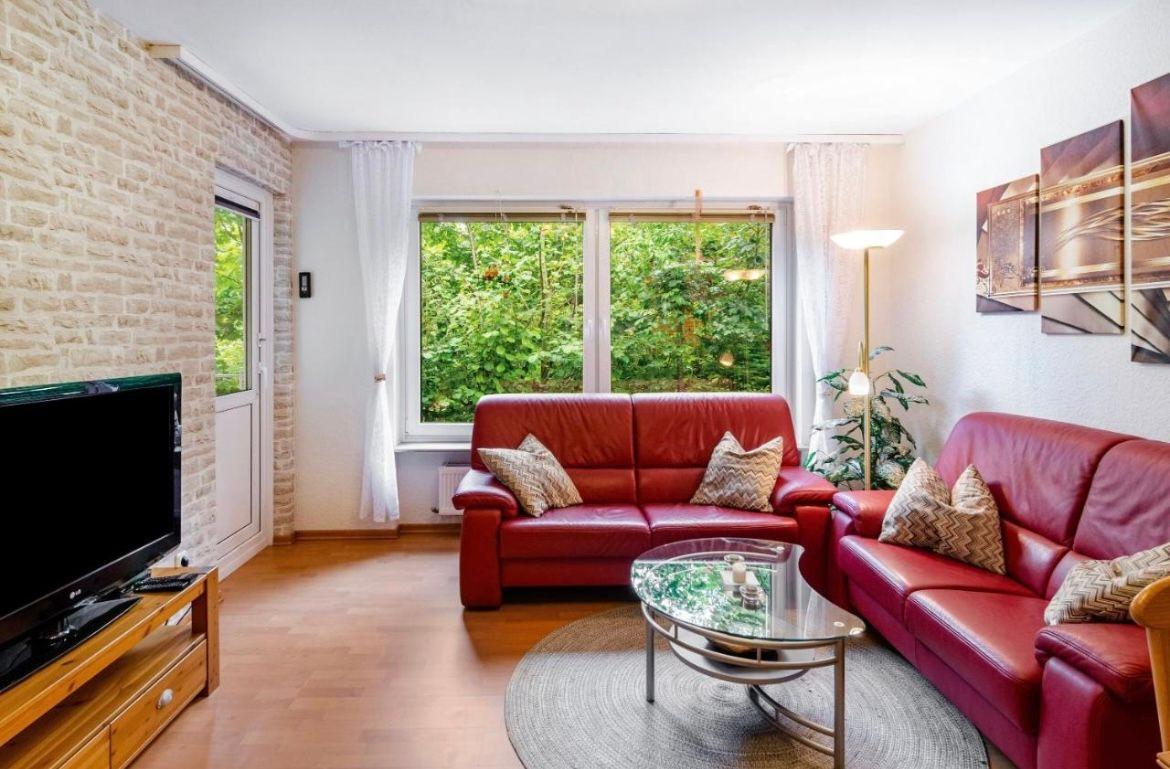 Wohnzimmer mit rotem Sofa, Glas-Tisch und Steinwand