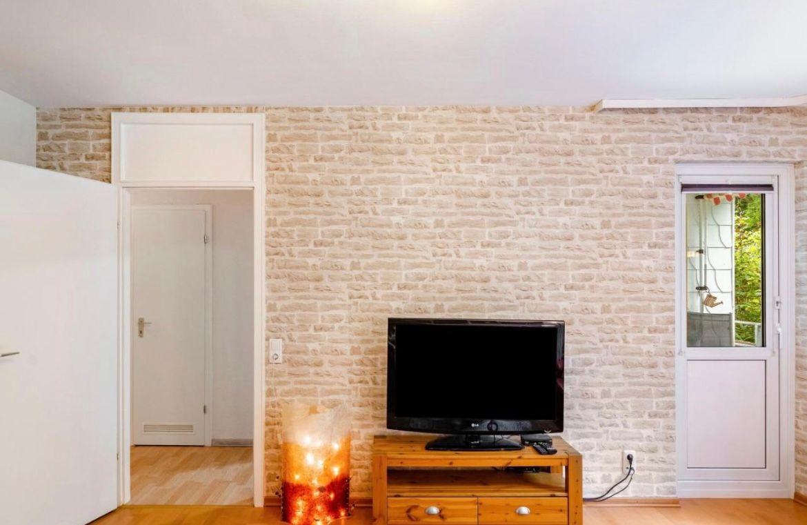 Wohnzimmer mit Steinwand, Fernseher und Tür zum Garten.