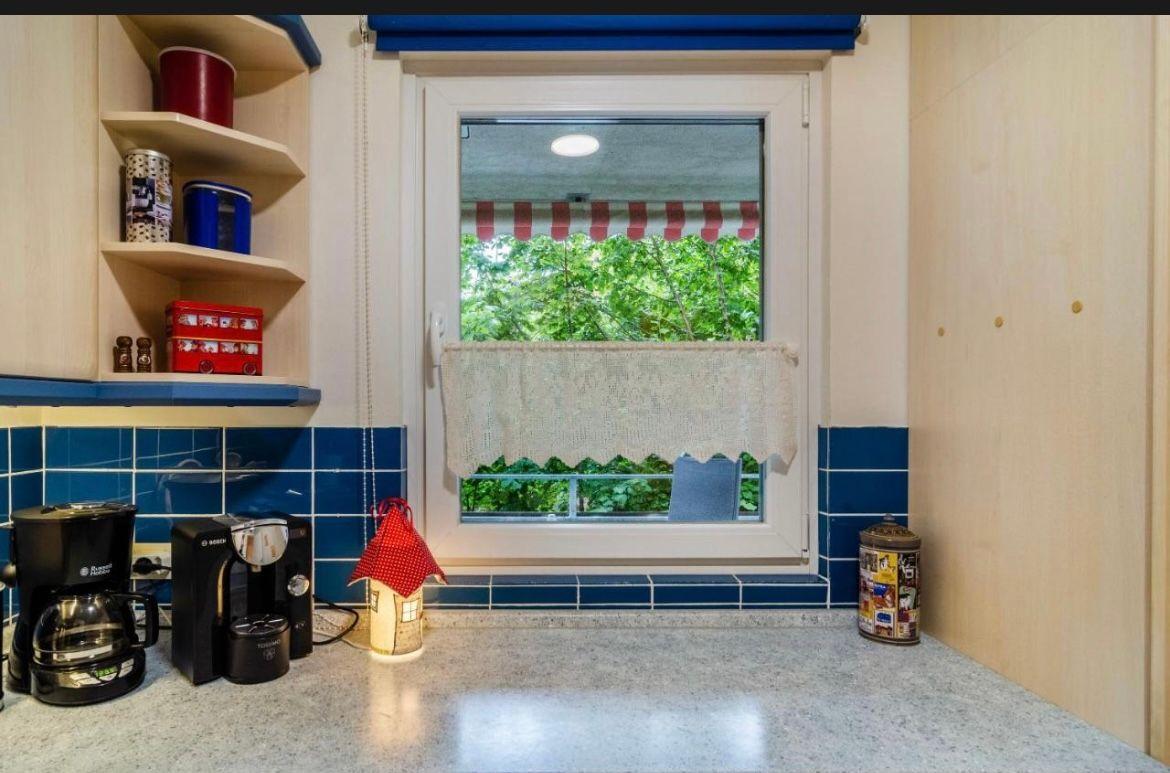 Küche mit Fenster, blauen Fliesen und Küchenutensilien.