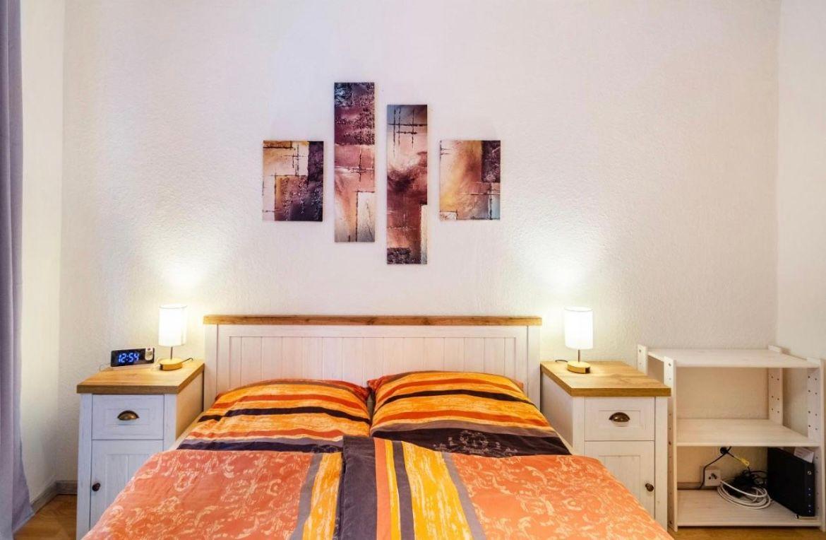 Schlafzimmer mit Doppelbett, Nachttischen und Wandbildern.