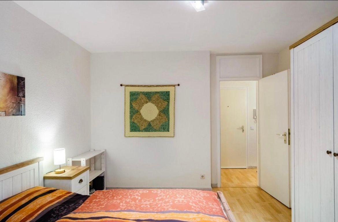 Schlafzimmer mit Bett, Nachttisch, Wandbild und Kleiderschrank.