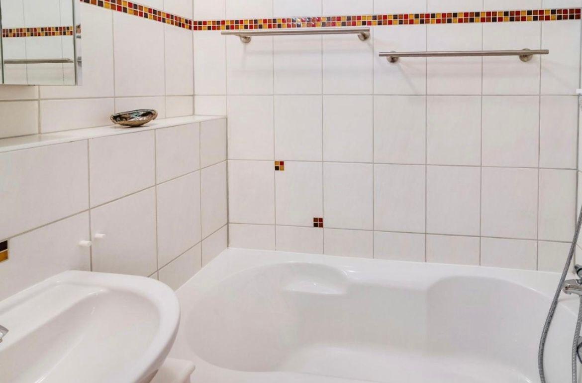 Badezimmer mit Badewanne, Waschbecken und Spiegel.