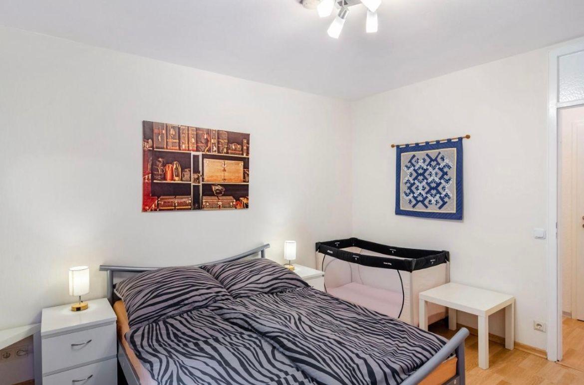 Schlafzimmer mit Bett, Wickelkommode und Wandbildern.