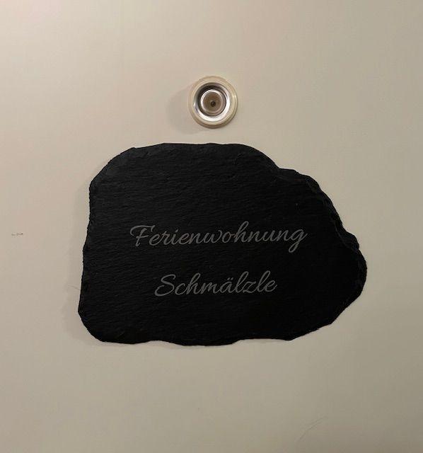 Schwarzer Stein mit Aufschrift Ferienwohnung Schmälzle und Duschkopf darüber